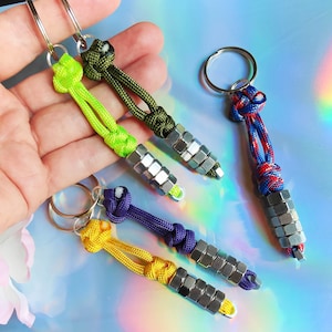 May include: Four keychains with different colored paracord and silver metal accents. The keychains are green, blue, yellow, and red.