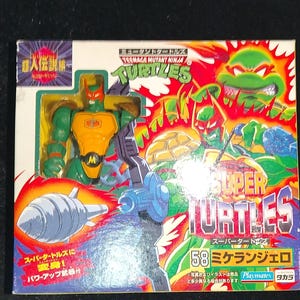 May include: A Teenage Mutant Ninja Turtles Super Turtles action figure in its original packaging. The packaging is colourful, featuring images of the characters and the text "Super Turtles". The figure is green, orange, and yellow.