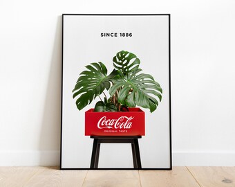 May include: A framed print featuring a vibrant green Monstera plant in a red Coca-Cola crate, set against a white background. The Coca-Cola logo and "ORIGINAL TASTE" are visible. The text "SINCE 1886" is at the top.