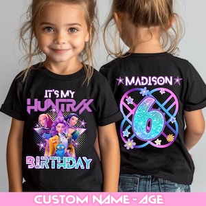 Könnte beinhalten: Schwarze T-Shirts mit einem farbenfrohen Grafikdesign. Auf der Vorderseite des Shirts steht "IT'S MY HUNTRAX BIRTHDAY" mit einem Cartoon-Bild. Auf der Rückseite des Shirts steht "MADISON" und die Zahl "6".