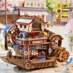 Peut inclure: Un modèle de puzzle 3D en bois représentant un restaurant de sushis nautique construit sur une structure de bateau. Il comprend des mécanismes à engrenages complexes, un bâtiment à plusieurs niveaux et des panneaux avec le texte Nautical Sushi.