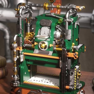 Puede incluir: Un complejo modelo de máquina de impresión hecho de bloques de construcción verdes y metálicos, con tuberías plateadas, engranajes dorados y un dial central. La base muestra el texto JAKI MAKER POP y la parte superior incluye un pequeño medidor verde.
