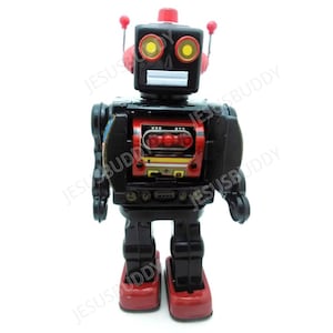 Pode incluir: Um robô de brinquedo vintage em preto e vermelho. O robô tem uma cabeça quadrada com olhos amarelos, uma boca branca e antenas vermelhas. O peito apresenta um painel vermelho com três luzes. Os pés do robô são vermelhos.