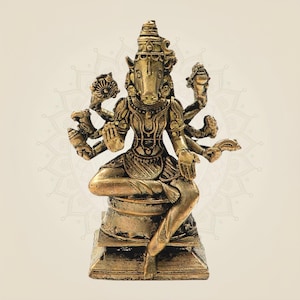 May include: A detailed bronze-colored statue of a deity with multiple arms and a boar's head. The figure is seated on a square base, adorned with intricate details, and wears ornate headwear. The statue has a weathered appearance.