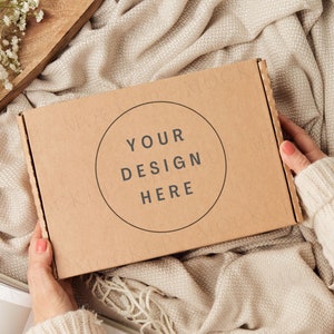 Mockup di confezione regalo con le mani. Mockup di scatola di spedizione marrone Kraft.