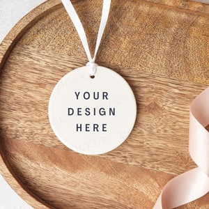 Round ceramic ornament keepsake mockup on wood with pink ribbon. Rustic wedding or valentine mock, Blank ceramic keepsake. Jpeg only.