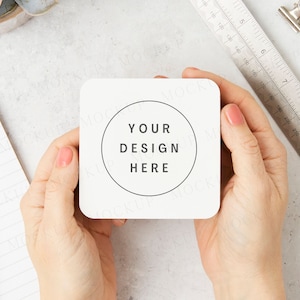 May include: A white square coaster with rounded corners. The coaster has a black circle in the center with the text "YOUR DESIGN HERE" inside.