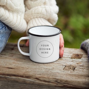Puede incluir: Taza de esmalte blanco con borde y asa negros. La taza tiene un círculo negro con el texto "YOUR DESIGN HERE" en el centro.