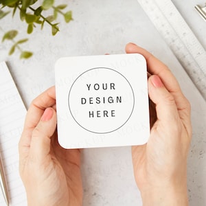 May include: A white square card with rounded corners held in two hands. The card has a circle in the center with the text "YOUR DESIGN HERE" inside.