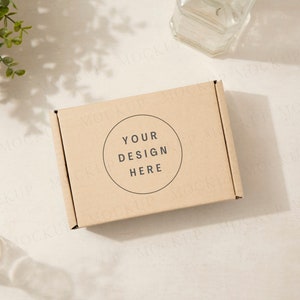 Mockup di confezione regalo con piante e ombre. Mockup di scatola di spedizione marrone Kraft con modello a mano. Sole screziato, giornata di sole.