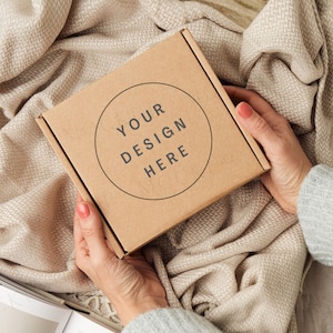 Mockup di confezione regalo con le mani. Mockup di scatola di spedizione marrone Kraft.