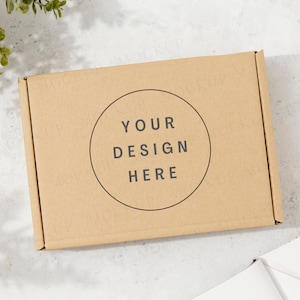 Mockup di confezione regalo con piante e ombre. Mockup di scatola di spedizione marrone Kraft. Sole screziato, giornata di sole.