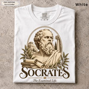 May include: A white t-shirt featuring a graphic print of Socrates in an oval frame. The design includes a bust of Socrates, a scroll, books, olive branches, and a Greek temple. The text reads SOCRATES and The Examined Life.