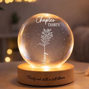 May include: A lit glass sphere with the words "Chapter THIRTY" and a floral design etched inside. The sphere sits on a wooden base that reads "Thirty and still in full bloom." The name "Henry" is also etched on the sphere.