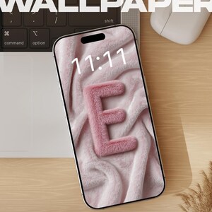 May include: A smartphone displaying a digital wallpaper with a soft pink faux fur texture and the letter E, showing the time 11:11. The screen includes text labels for Lock Screen, iOS & Android, No Watermark, 4K Ultra HD, Instant Download, and BUY NOW.