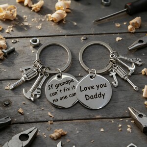 May include: Two silver keychains with round pendants and tool charms. One keychain says "If grandpa can't fix it no one can." The other says "Love you Daddy." The charms include a hammer, wrench, and screwdriver.