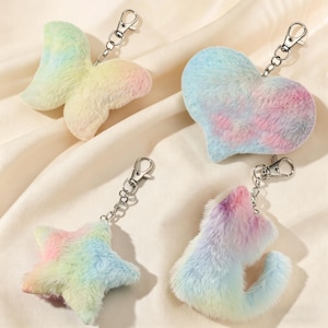 Peut inclure: Quatre porte-clés en forme de papillon, de cœur, d'étoile et de chat. Chaque porte-clés est fait de fausse fourrure douce et colorée aux teintes arc-en-ciel pastel. Les porte-clés ont des fermoirs en métal argenté pour une fixation facile.