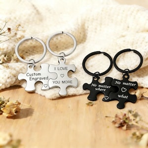 May include: Two sets of puzzle piece keyrings. One set is silver with the words "Custom Engraved" and "I Love You More." The other set is black with the words "No matter where" and "No matter what."