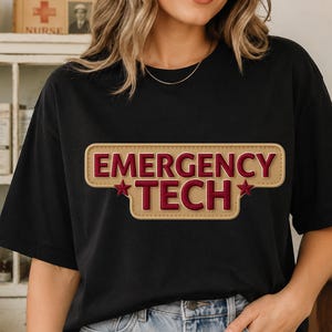 May include: A black short-sleeved t-shirt featuring a tan rectangular patch graphic with rounded corners. The text EMERGENCY TECH is printed in bold dark red capital letters, flanked by two small dark red stars on the middle line.