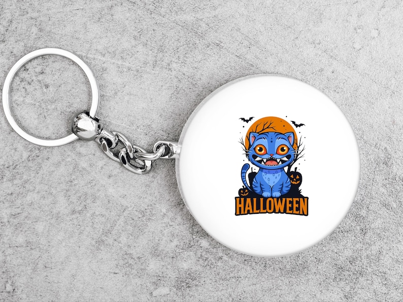 May include: A white keychain with a round charm featuring a blue cartoon cat with orange eyes and sharp teeth. The cat is set against an orange moon with bats and bare trees. The word "HALLOWEEN" is below the cat.