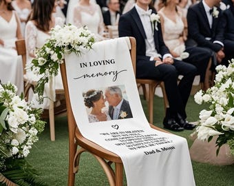 May include: A white fabric chair sash with the words "IN LOVING memory" and a photo of a couple. Below the photo is the text "WE ARE IN HEAVEN...WE WILL BE THERE...Dad & Mom". The sash is draped over a wooden chair at a wedding.