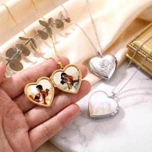 May include: Three heart-shaped locket necklaces on thin metal chains. One gold locket is open, revealing two photographs of a person. One silver locket features an embossed rose design, and another silver locket has a smooth, iridescent shell-like finish.