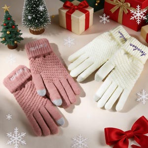 May include: Knitted gloves in pink and cream, with grey touch-screen fingertips. The pink gloves have "Courgette" embroidered on the cuff, while the cream gloves say "Aurelian". The gloves are displayed with gift boxes and Christmas decorations.