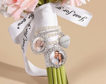 Può includere: Un bouquet di fiori rosa e bianchi con un nastro di raso bianco che riporta la scritta Just for you. L'impugnatura è avvolta in tessuto bianco e decorata con due ciondoli portafoto argentati e un ciondolo a forma di cuore con Be with you.