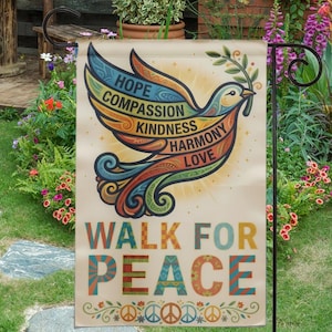 Puede incluir: Una bandera de jardín con un diseño de paloma y las palabras "ESPERANZA, COMPASIÓN, BONDAD, ARMONÍA, AMOR" en un esquema de colores arcoíris. La bandera también dice "CAMINA POR LA PAZ" en letras coloridas, con símbolos de paz en la parte inferior. La bandera se muestra en un jardín.