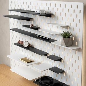 Può includere: Una tazza di ceramica bianca con manico nero e la scritta "But First, Coffee" in nero, con un carattere a mano. La tazza è su una superficie bianca.
