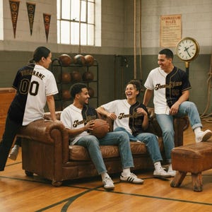 May include: A split-colour baseball jersey featuring a black left side and white right side with gold lettering that reads Team Name and the number 00. The shirt has a button-down front, short sleeves, and a classic collar, worn by four individuals.