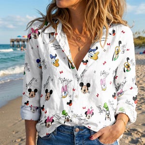 May include: A white long-sleeve button-down shirt featuring an all-over print of various Disney characters including Mickey Mouse, Minnie Mouse, Donald Duck, Daisy Duck, Pluto, and Goofy, interspersed with small red bows and character names.