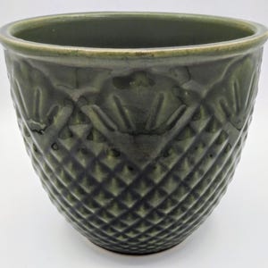 May include: A dark green ceramic planter with a diamond pattern. The planter has a wide opening and a slightly textured surface. The color is a deep, earthy green, suitable for indoor or outdoor use. The design is a classic, timeless style.
