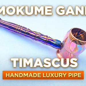 Puede incluir: Una pipa de lujo hecha a mano con un diseño Mokume Gane y Timascus. La pipa presenta un acabado metálico con tonos de morado, azul y dorado. Se muestra el texto "MOKUME GANE", "TIMASCUS" y "HANDMADE LUXURY PIPE".