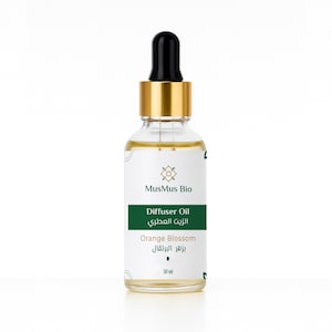 May include: A clear glass bottle of MusMus Bio Diffuser Oil, Orange Blossom scent. The bottle has a gold cap and a black dropper. The label is white with green accents and text in English and Arabic. The bottle contains 30 ml of oil.
