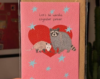 Illustrated funny anniversary card. Raccoon and opossum - let's be weirdos together forever