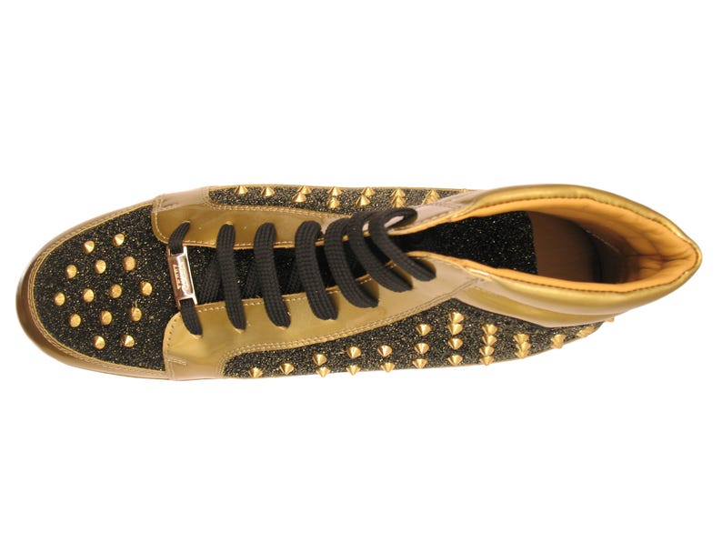 Puede incluir: Zapatilla alta dorada y negra con cordones negros. El zapato presenta detalles dorados, puntera y tal&oacute;n negros brillantes y tachuelas doradas. El interior es de color marr&oacute;n claro.