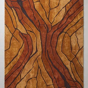 May include: A rectangular area rug featuring a textured, abstract pattern of interlocking shapes in shades of burnt orange, golden yellow, and deep brown. The design is defined by dark, recessed lines that create a cracked or fragmented appearance.
