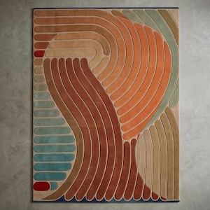 May include: A rectangular area rug with an abstract design. The rug features curved, parallel lines in shades of orange, brown, beige, and teal. A red accent is at the top left corner. The rug has a dark blue border.