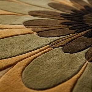 Puede incluir: Primer plano de una alfombra con estampado floral y superficie texturizada. La alfombra presenta un dise&ntilde;o de p&eacute;talos superpuestos en tonos marr&oacute;n, beige y verde oliva. Las fibras de la alfombra crean una apariencia suave y afelpada, adecuada para la decoraci&oacute;n del hogar.