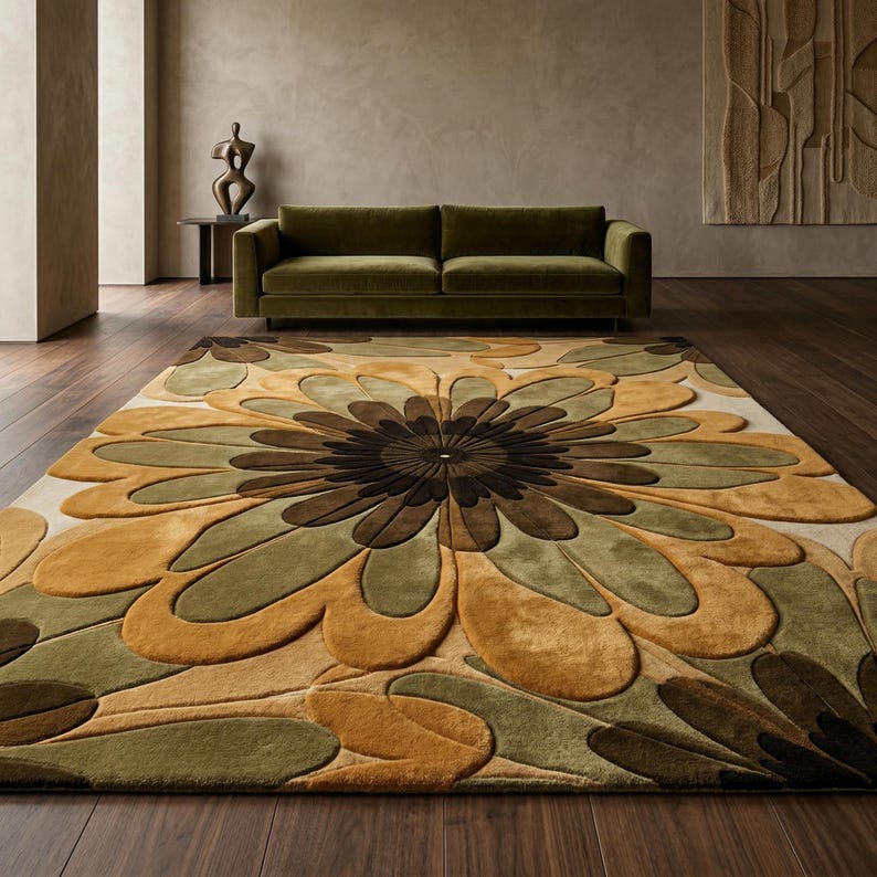 Puede incluir: Una alfombra rectangular grande con un dise&ntilde;o floral en tonos marrones, verdes y beige. La alfombra est&aacute; colocada sobre un suelo de madera oscura, con un sof&aacute; verde en el fondo. El patr&oacute;n de la alfombra se asemeja a una flor grande.