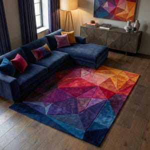 K&ouml;nnte beinhalten: Ein modernes Wohnzimmer mit einem marineblauen Ecksofa und bunten Kissen. Ein geometrischer Teppich in Blau-, Lila-, Rot- und Oranget&ouml;nen bedeckt den Boden. Ein passendes Kunstwerk an der Wand erg&auml;nzt das Design des Teppichs.