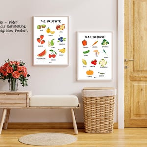 May include: Two framed prints on a wall, one labeled "DIE FR&Uuml;CHTE" with illustrations of fruits like apples, strawberries, and bananas. The other print, "DAS GEM&Uuml;SE," displays vegetables such as carrots, tomatoes, and broccoli. A bench, basket, and flowers are in the foreground.