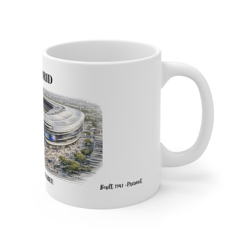 Pu&ograve; includere: Una tazza in ceramica bianca con una dettagliata illustrazione architettonica di uno stadio. Il testo riporta MADRID, SANTIAGO BERNABEU e Built 1947-Present. Il design mostra una vista aerea della struttura dello stadio con alberi.