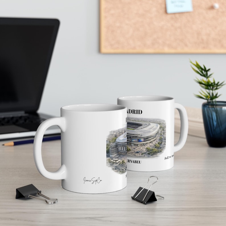Pu&ograve; includere: Due tazze in ceramica bianca con un'illustrazione architettonica dettagliata dello stadio Santiago Bernab&eacute;u di Madrid. Il design include il testo MADRID e BERNABEU, con un piccolo logo in corsivo con la scritta IconicSipCo su una tazza.