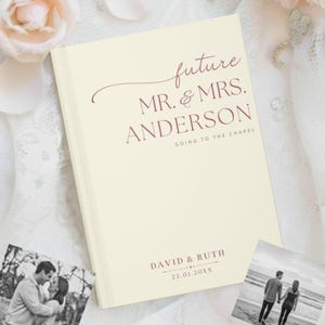 Peut inclure: Livre d'or de mariage ivoire avec texte bordeaux "future MR. & MRS. ANDERSON GOING TO THE CHAPEL". Le bas du livre porte les noms "DAVID & RUTH" et une date. Deux photos en noir et blanc sont en arrière-plan.