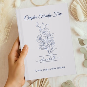 May include: A white book cover with the title "Chapter Twenty Five" in navy blue script. A floral illustration and the name "elizabeth" are below the title. The text "A new page, a new chapter" is at the bottom.