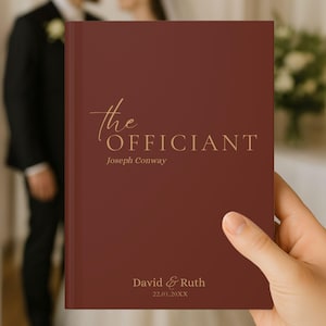 Puede incluir: Un libro de color burdeos con letras doradas. La portada dice "the Officiant" y el nombre "Joseph Conway". La parte inferior del libro tiene los nombres "David & Ruth" y la fecha "22.01.20XX".