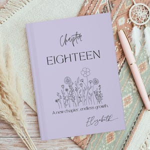 May include: A lavender journal with the words "Chapter EIGHTEEN" in black script. Below the text is a floral illustration and the words "A new chapter, endless growth." The name "Elizabeth" is written in script at the bottom.