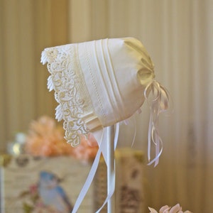 Beautiful white cotton baby bonnet edged with heavy lace and tucks. Cotton Cottagecore baby cap.